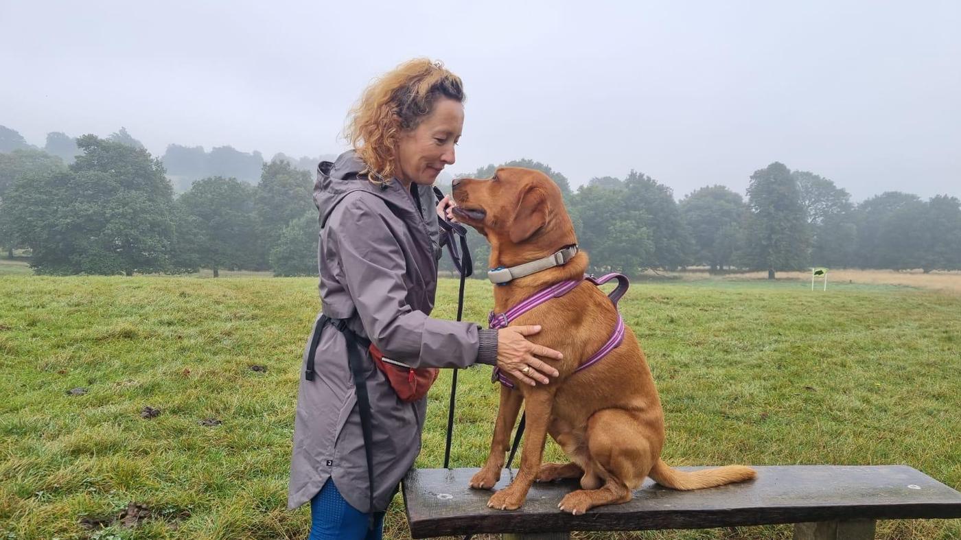 Flo Baker-Berry, dog behaviourist in Bingham Nottinghamshire, with a fox red labrador in a misty field